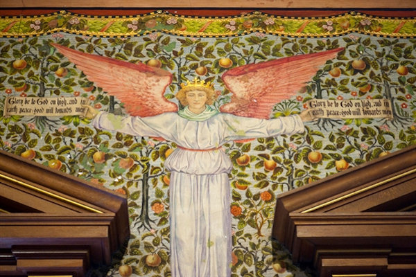 Painted fresco depicting an angel above the stained glass windows